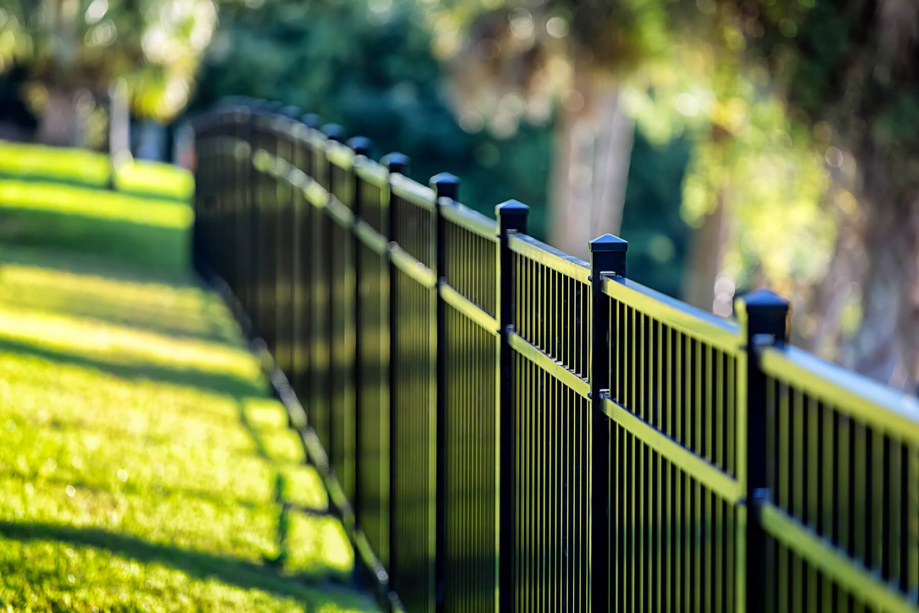 Black wrought iron fence with blurred, green landscape in the background.